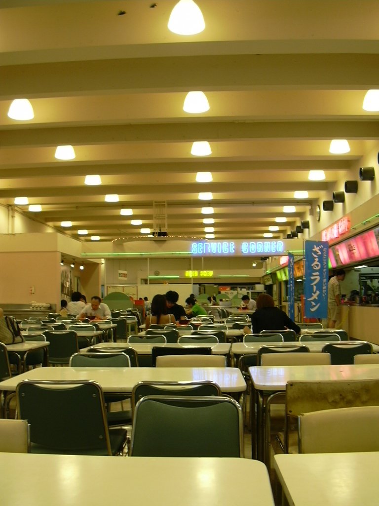 people are sitting and walking through an empty cafeteria