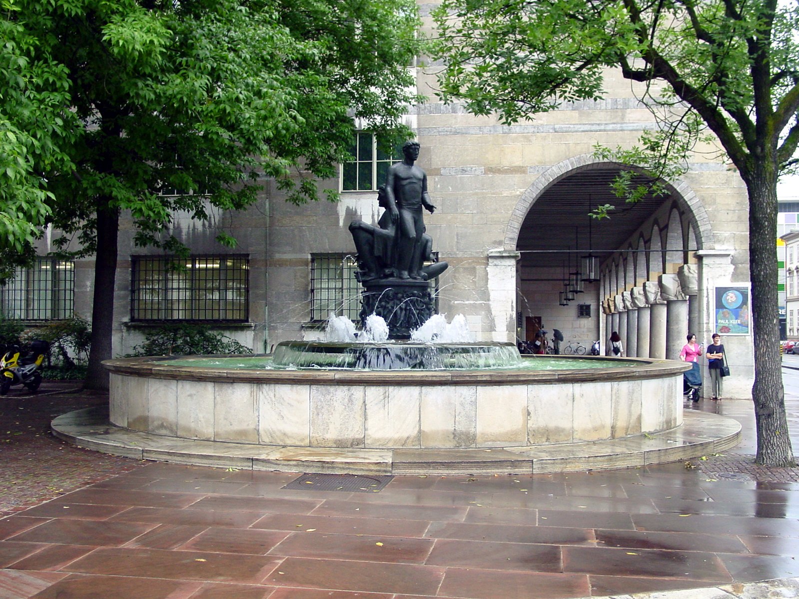 a man standing next to a fountain in front of a building