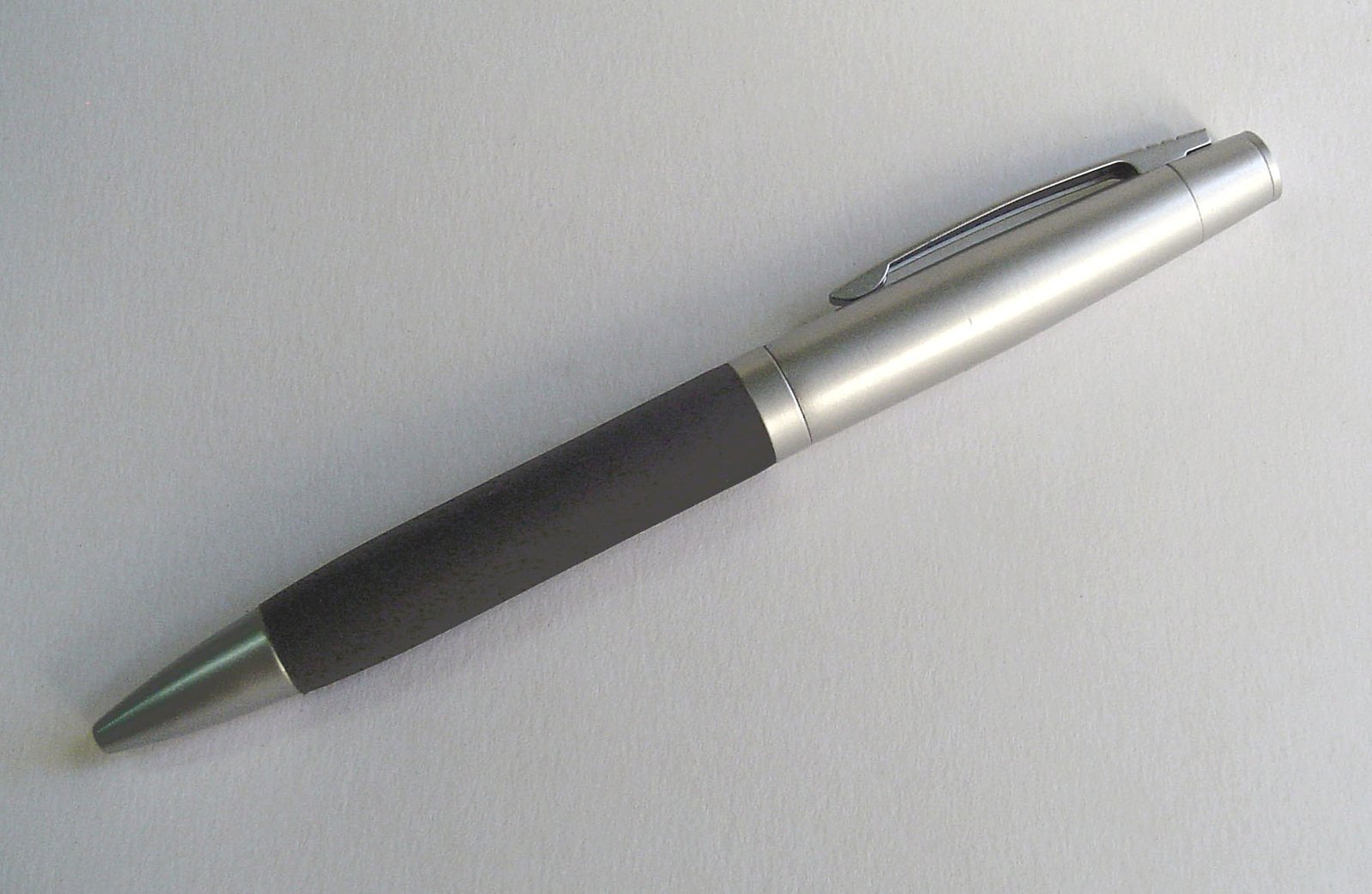 a pen resting on a white surface with the tip in the air