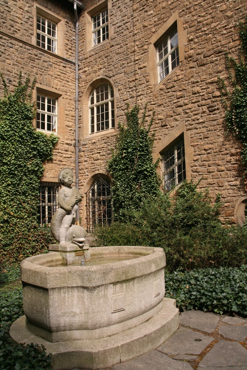 a statue sits in a fountain in front of a brick building