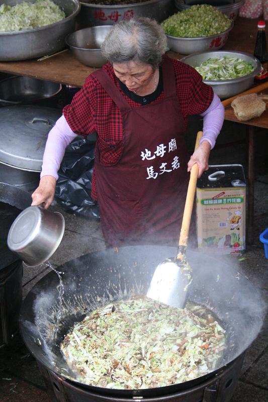 an old woman cooks some food inside of a pan