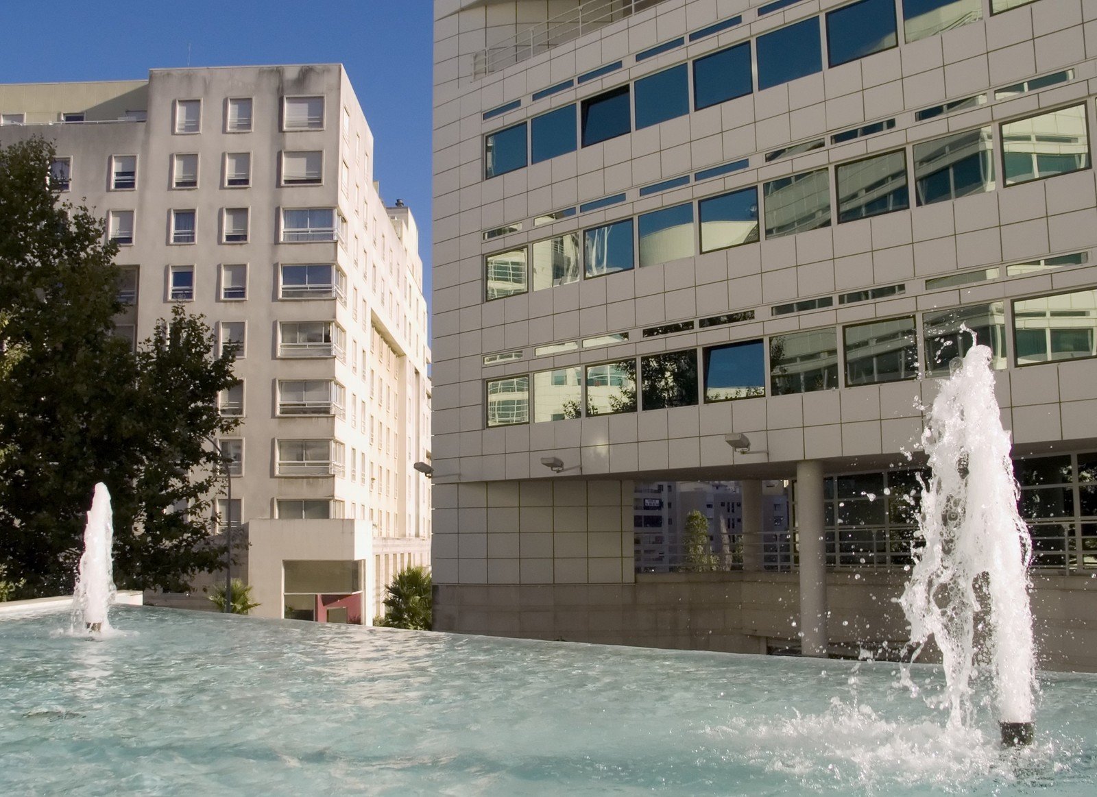 the fountains are spouting and spraying water in front of the building