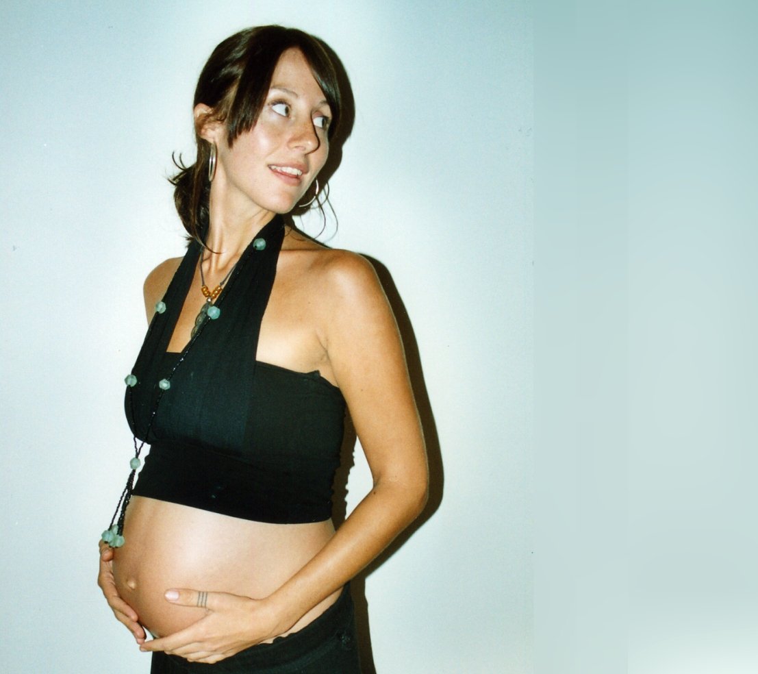 a pregnant woman poses for the camera in a black top