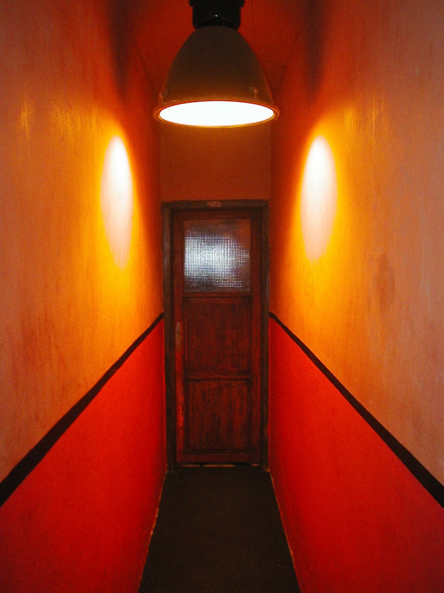 a hallway with a red wall and two lamps