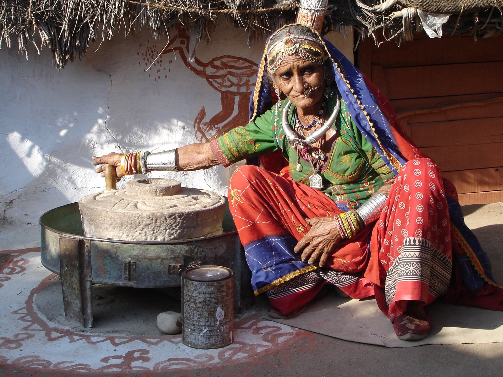 the woman is wearing colorful clothing while sitting next to a large bowl