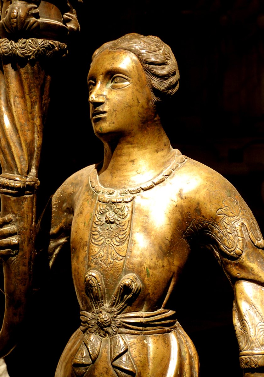 a golden statue of a woman holding a lamp