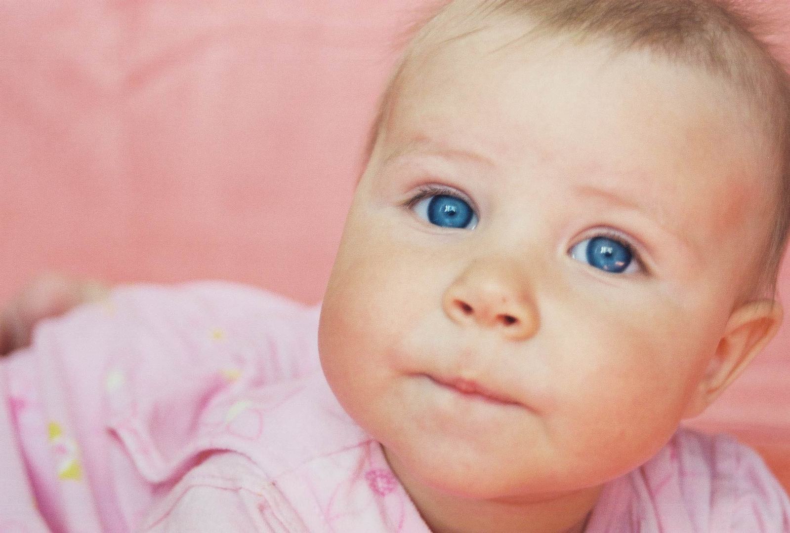 a very cute blue eyed baby in a pink dress