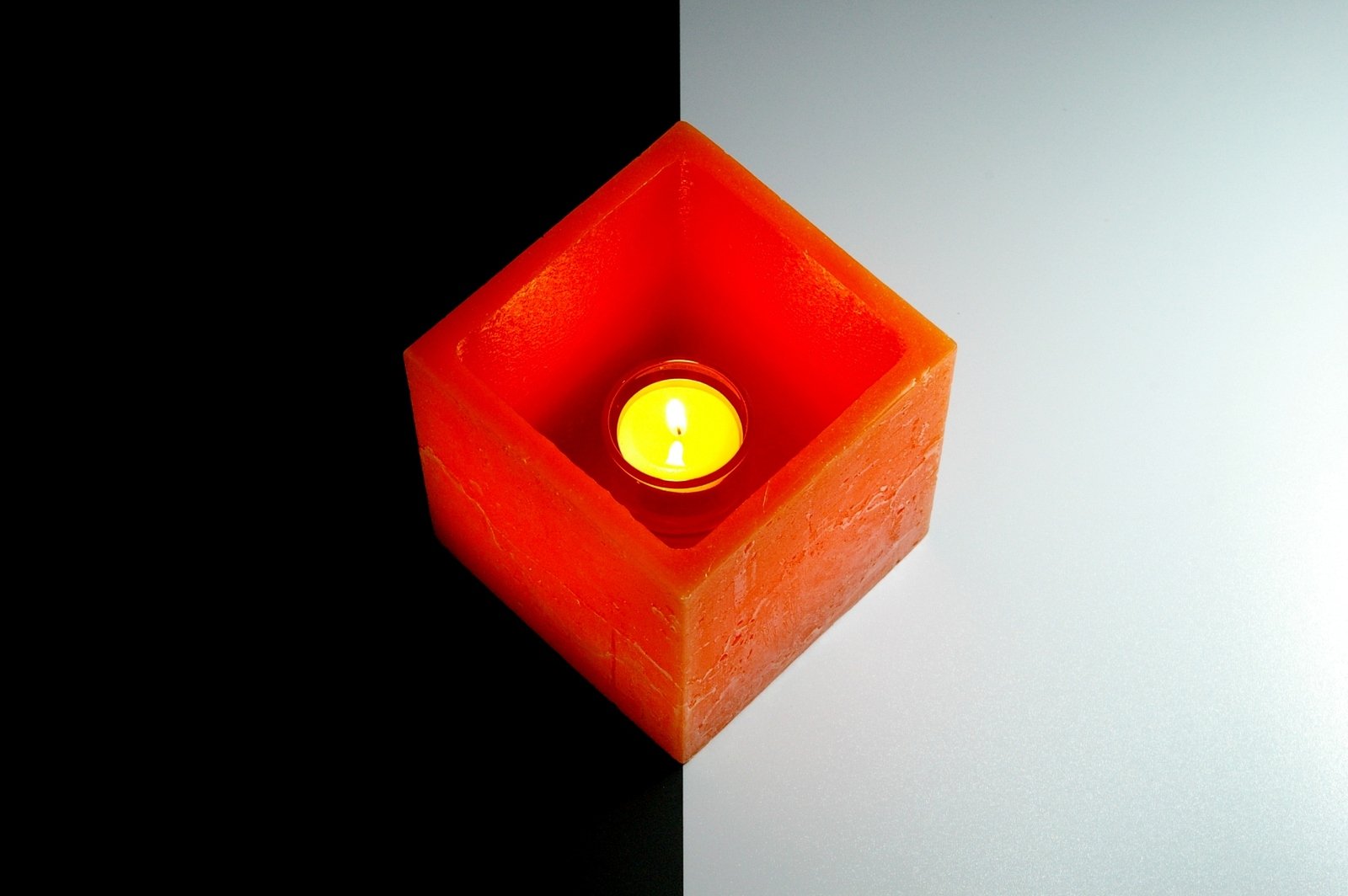 a candle light sitting in a red cube