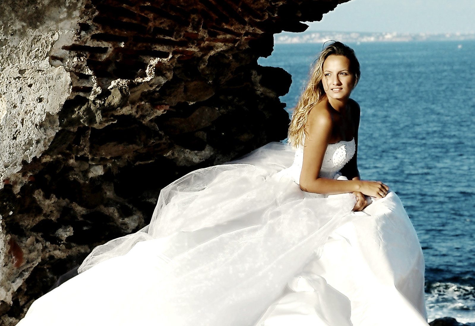 a woman in a long white dress on a rocky cliff