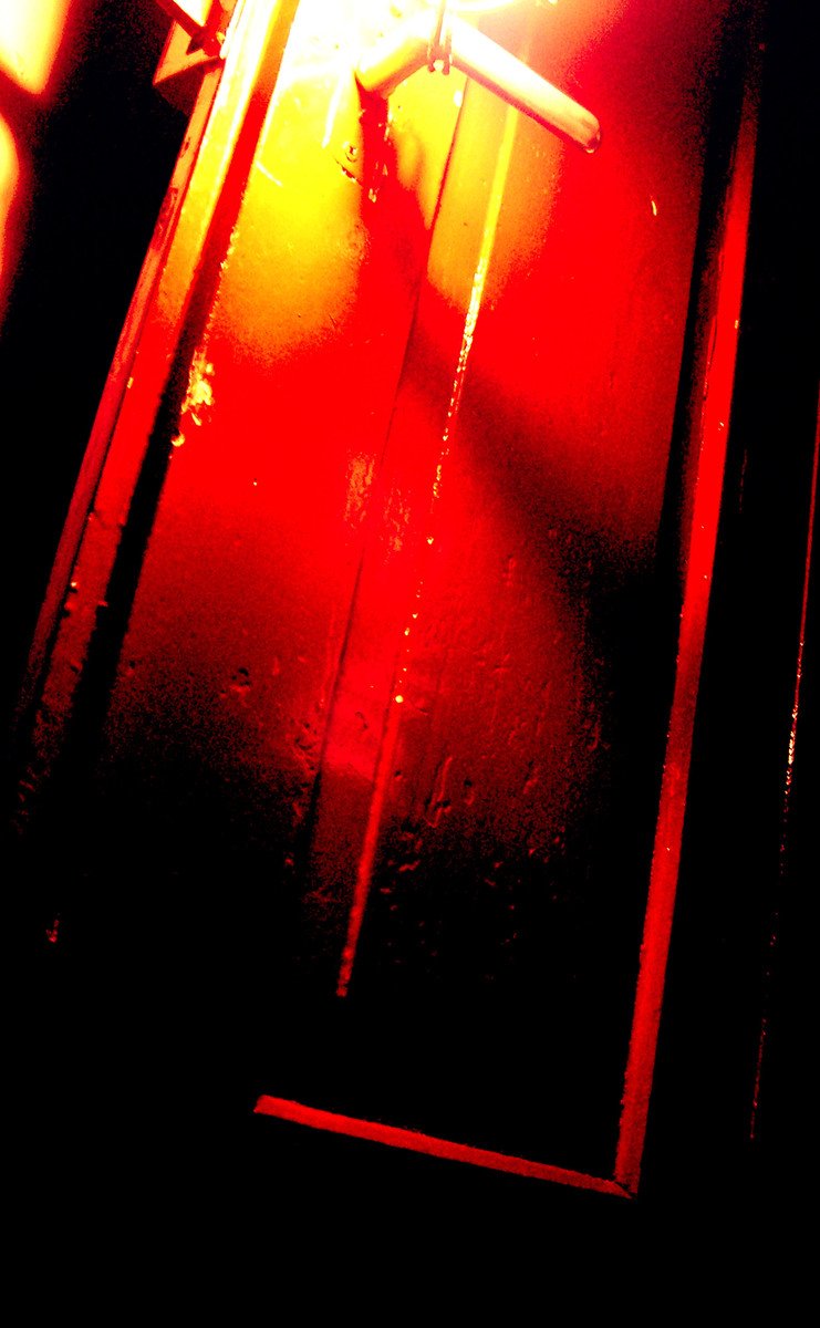 an outdoor light and mirror reflect a red and yellow light