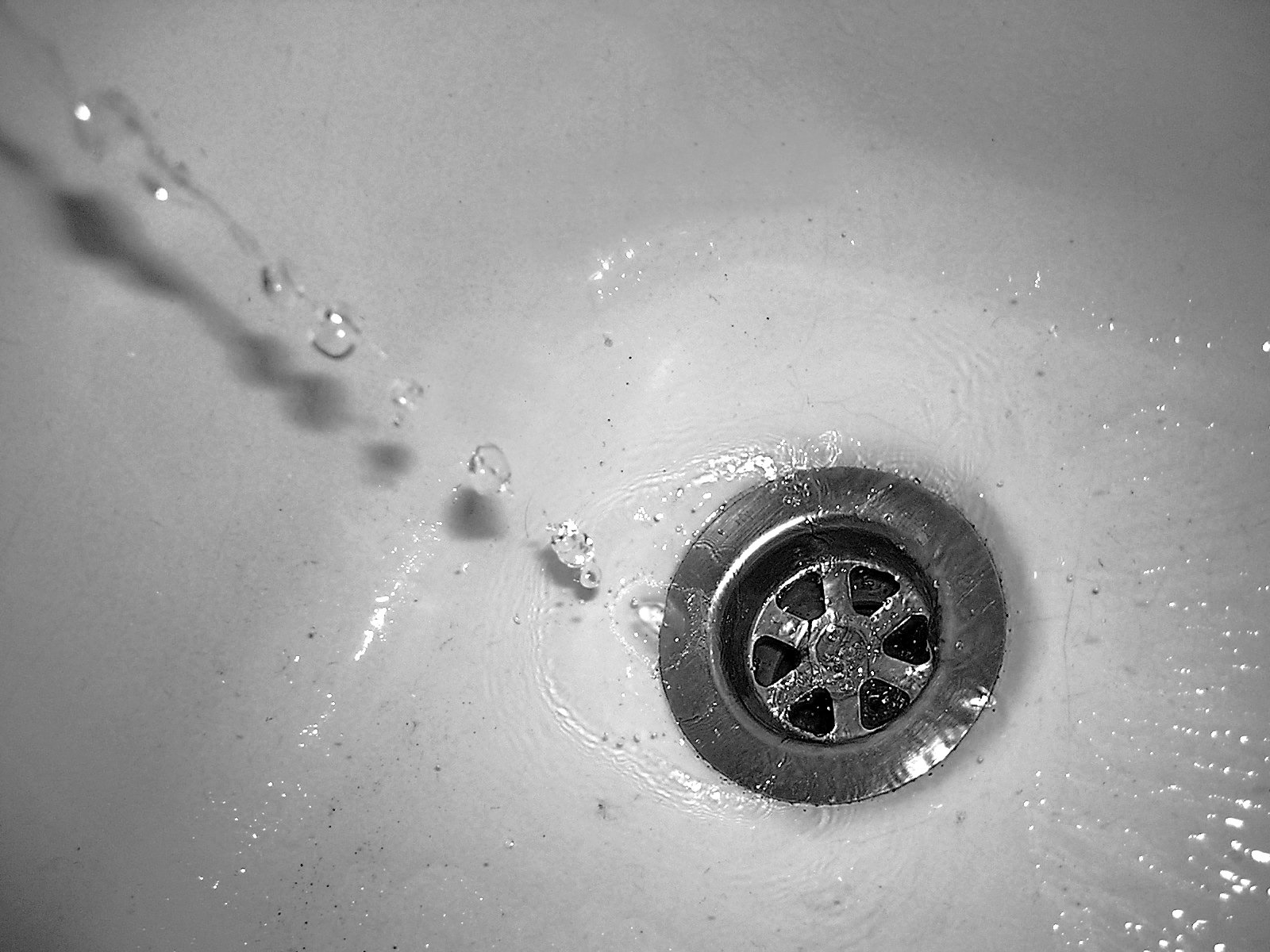black and white po of a sink with water coming out