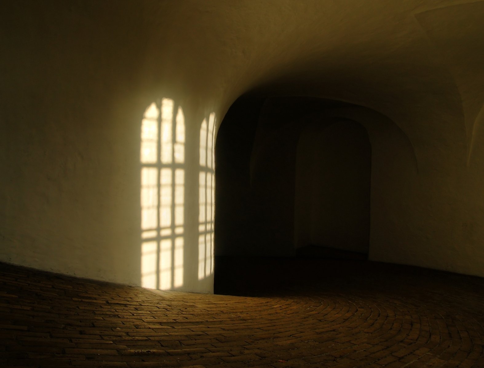 bright window shining in between two white walls in a dimly lit building