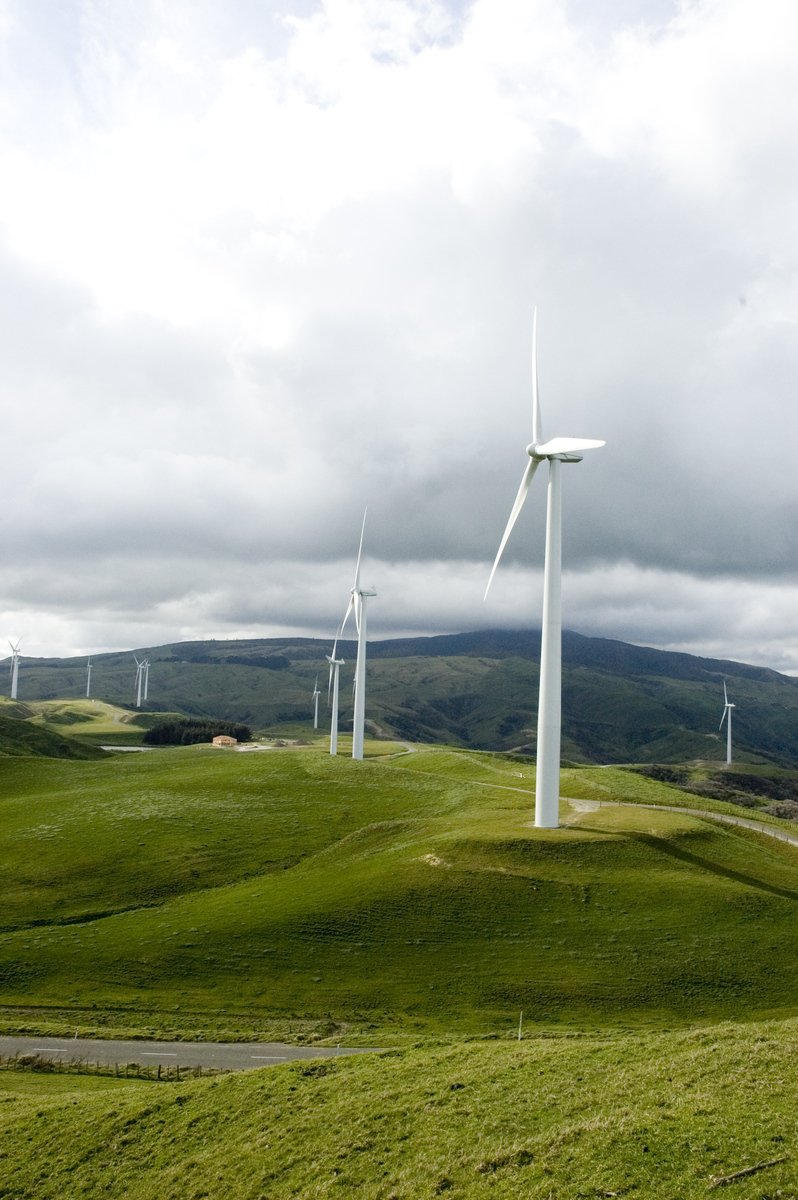 some wind mills sit on the green grass