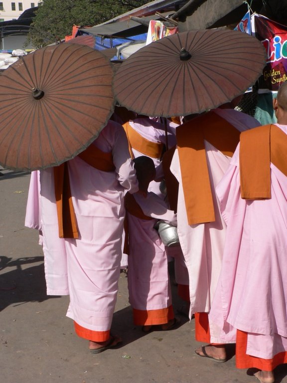 three women dressed in pink are standing under umbrellas