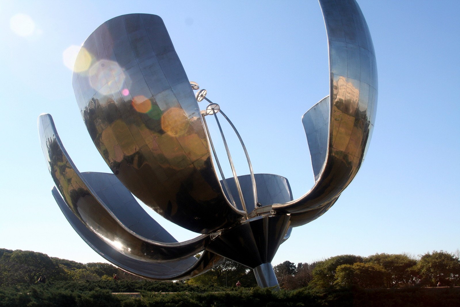 a large sculpture with curved legs in front of some hills