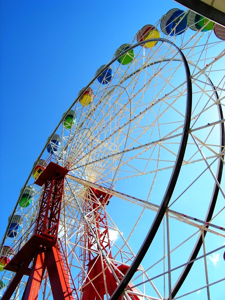 a ferris wheel is brightly lit and the sky is blue