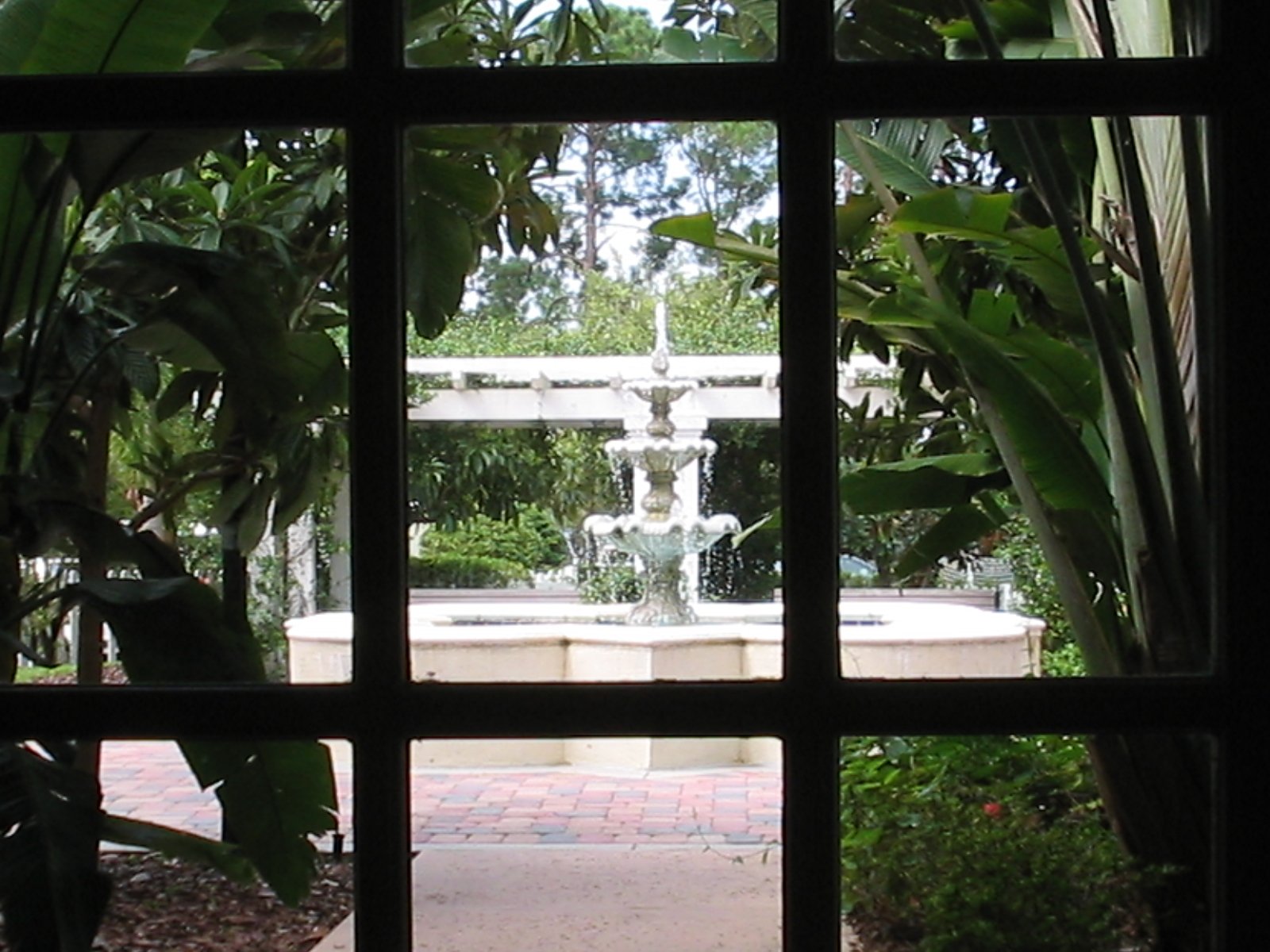 looking through windows to a park with fountains
