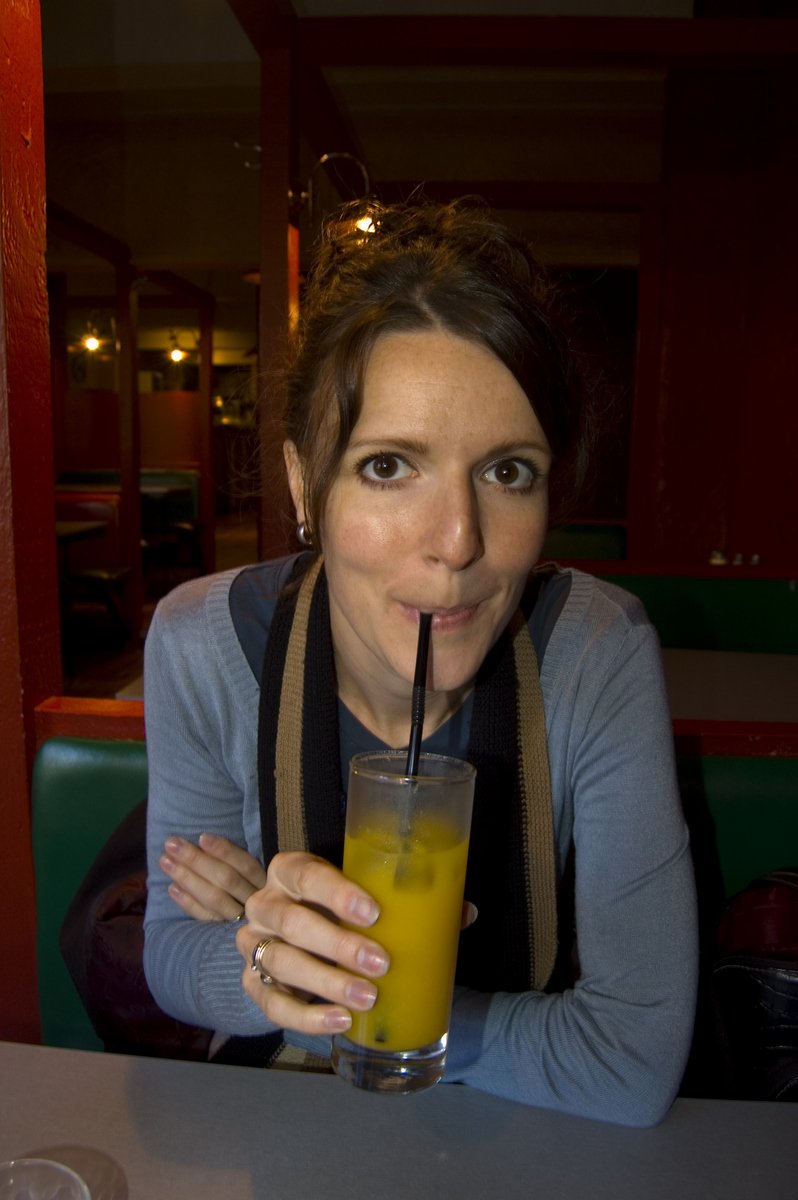 a woman holds a glass of liquid in her mouth