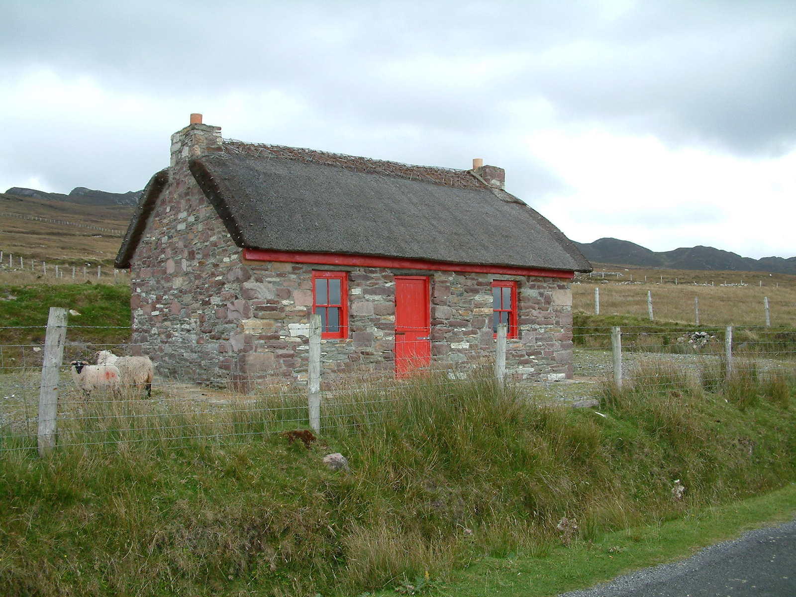 small stone building with red door and grass yard