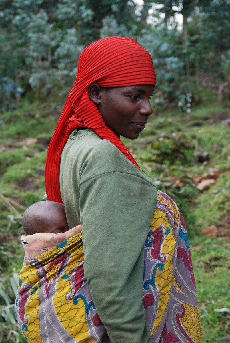 a woman in red head covering holding a baby