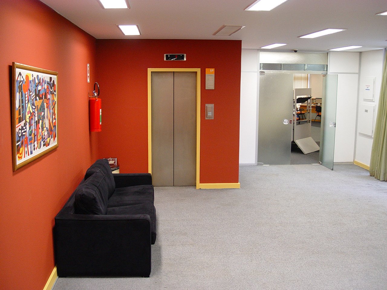an orange and red wall with a black couch in the middle