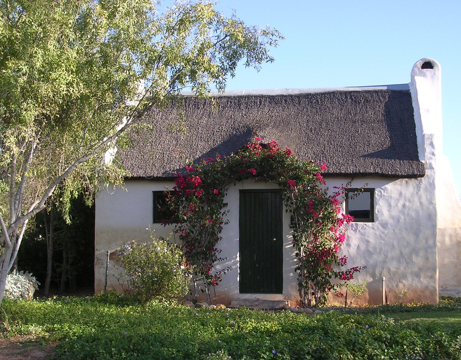 the entrance to the cottage has pink flowers on it