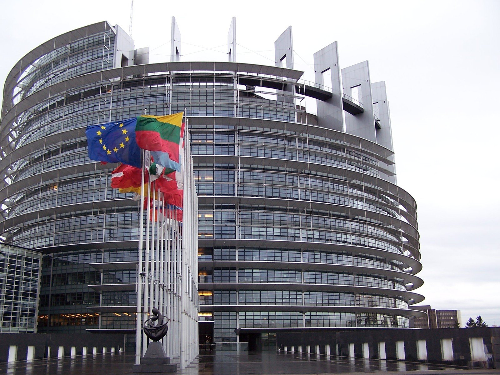 the european parliament building in brussels has a multi - colored flag flying from it