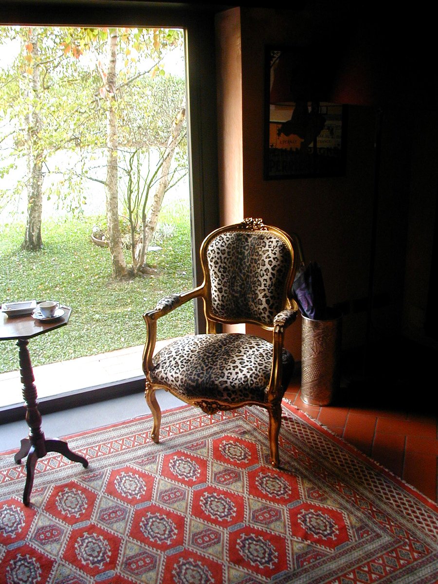 an arm chair sitting in front of a window near a chair
