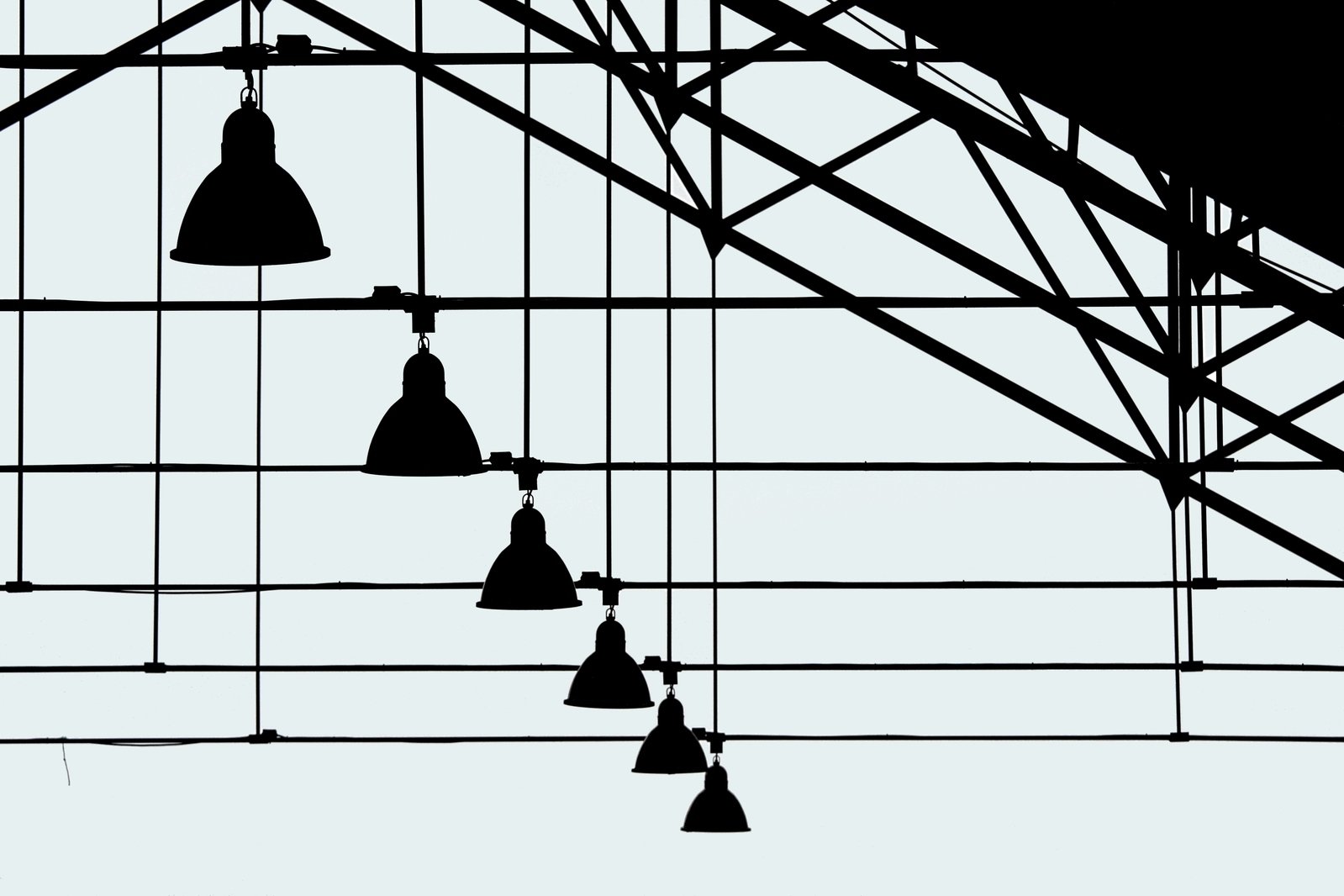 a black and white image of several lights suspended from metal beams