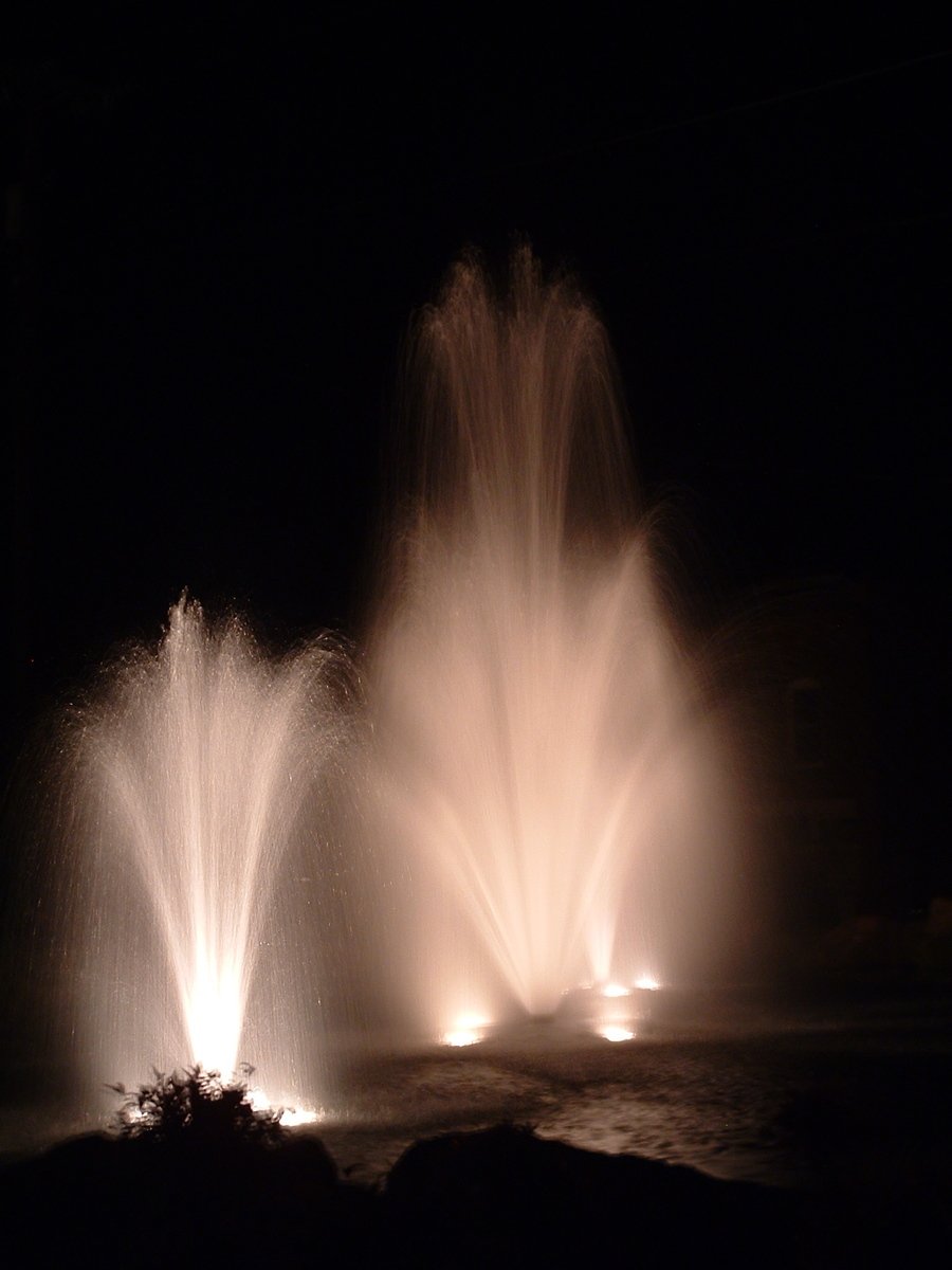 three fountains show brightly white colors in a dark landscape