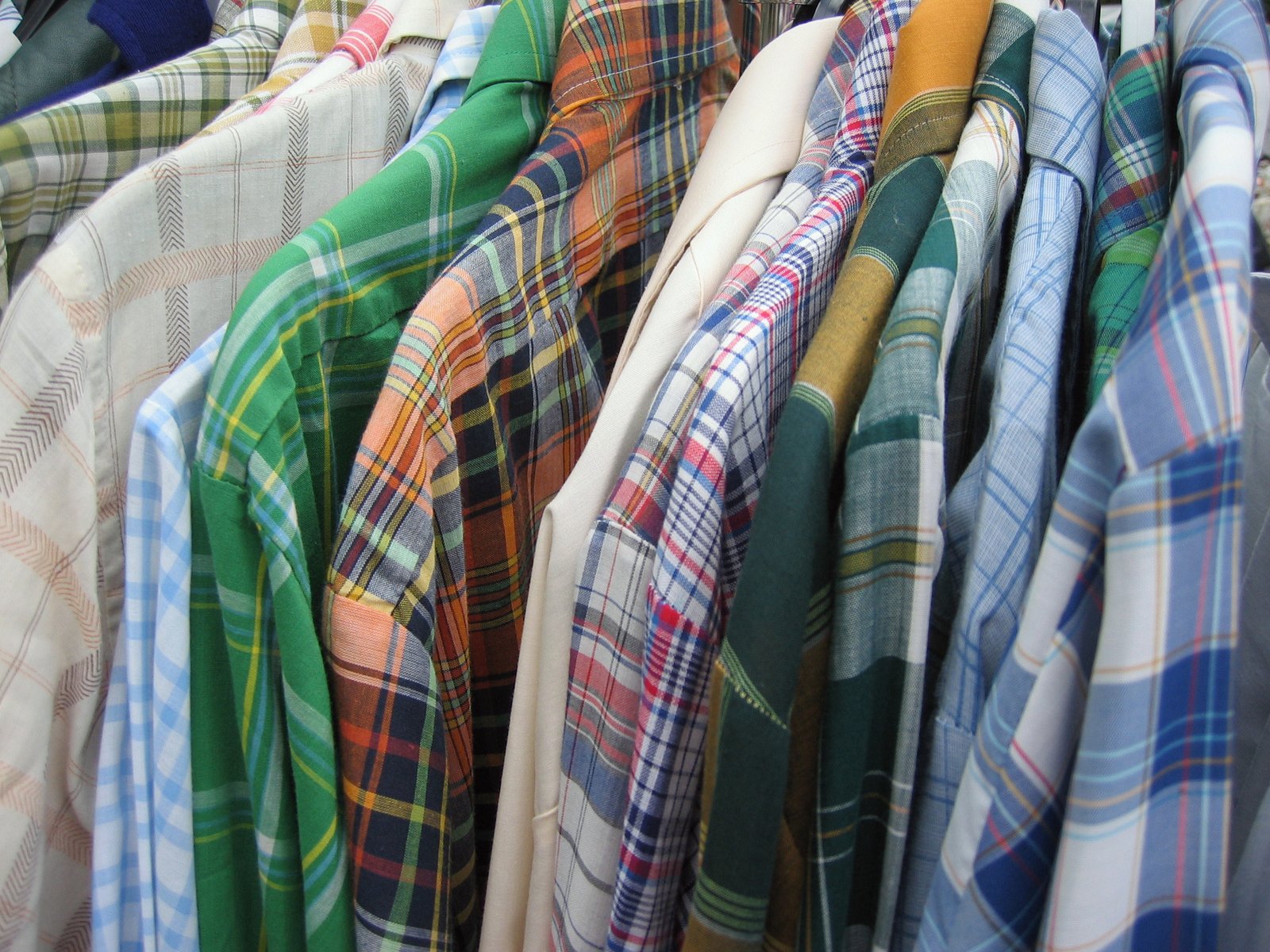 a row of folded shirts and scarves hanging up