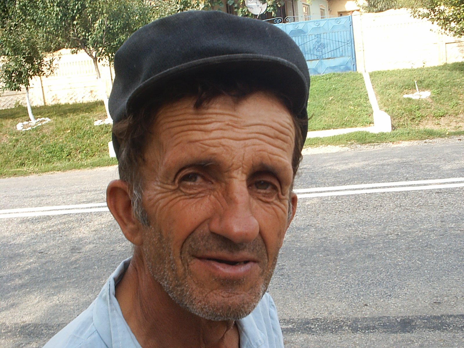 a man in a blue shirt and a black hat smiles