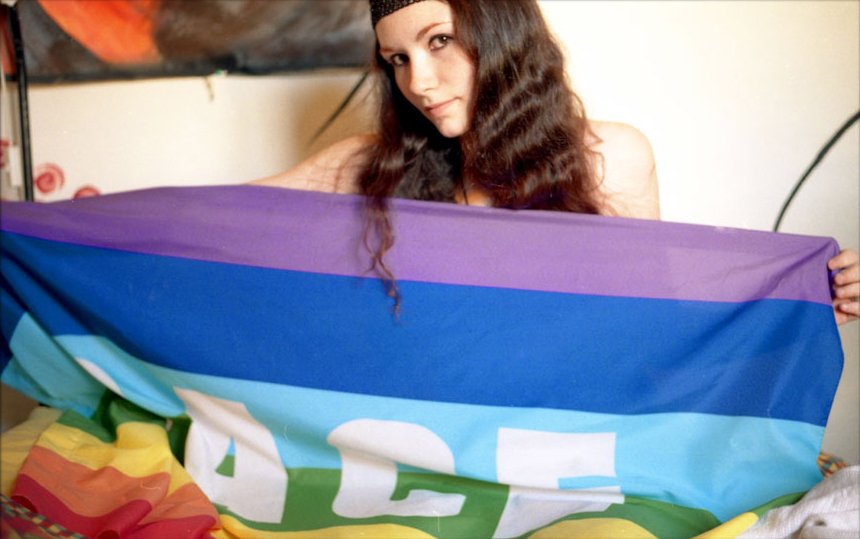 a young woman holds a large rainbow colored blanket
