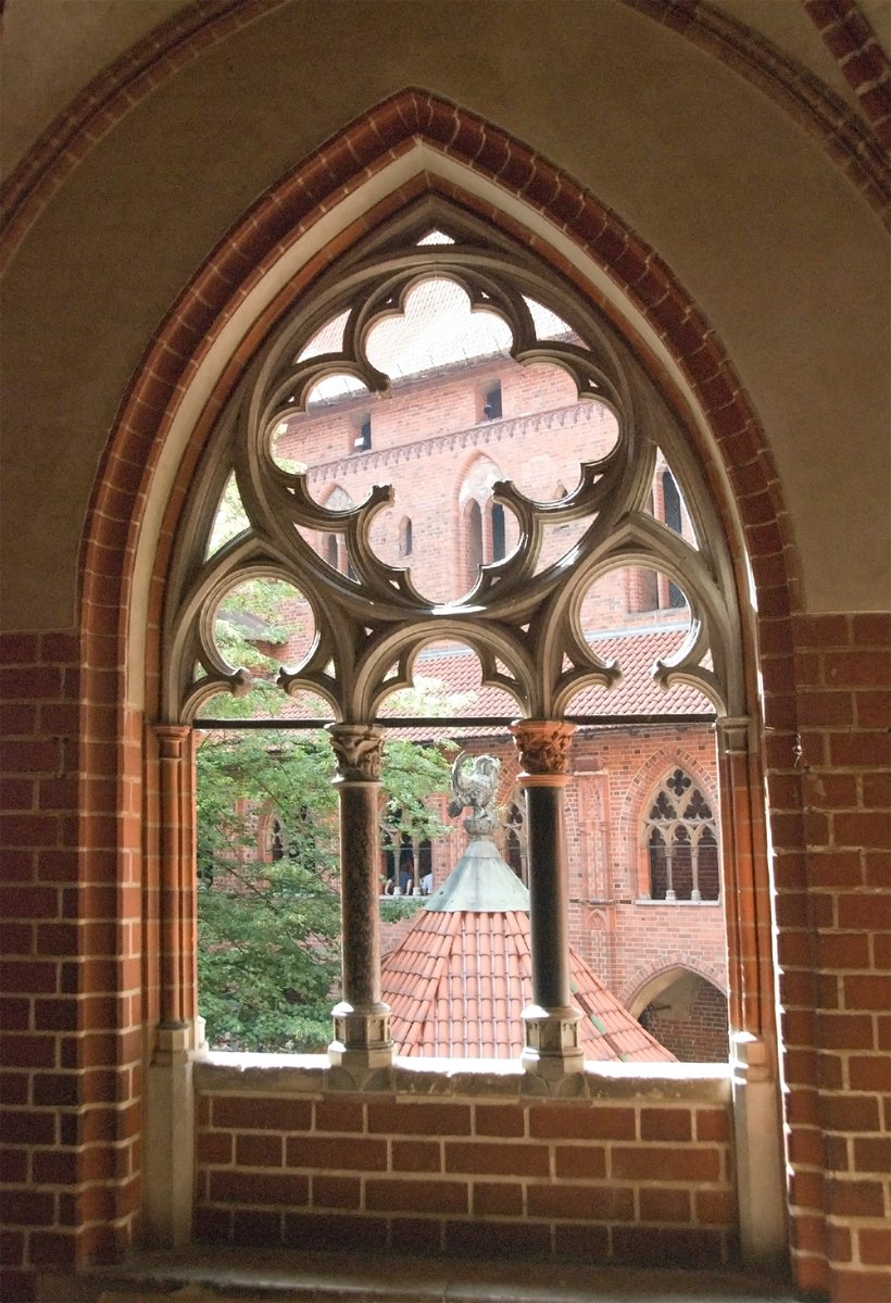 a cathedral with a beautiful arched window with statues outside it