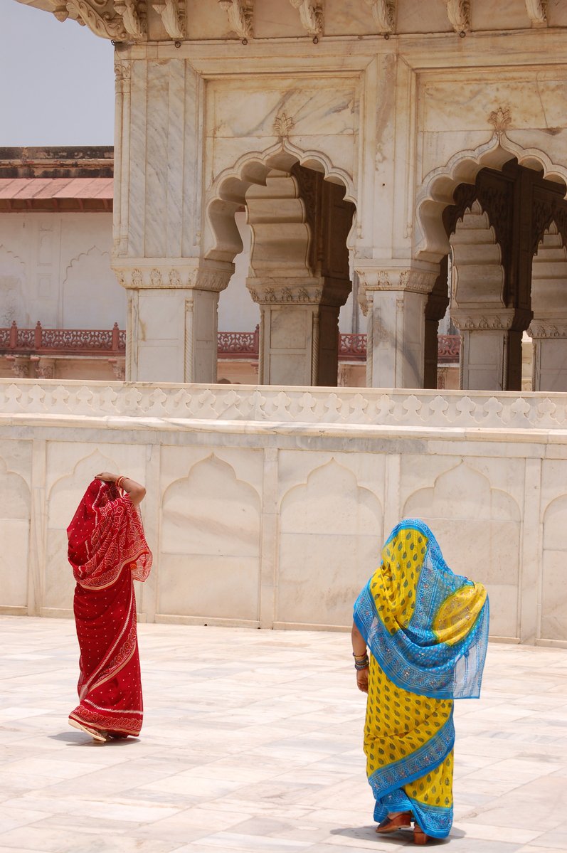 two women dressed in different color outfits stand together