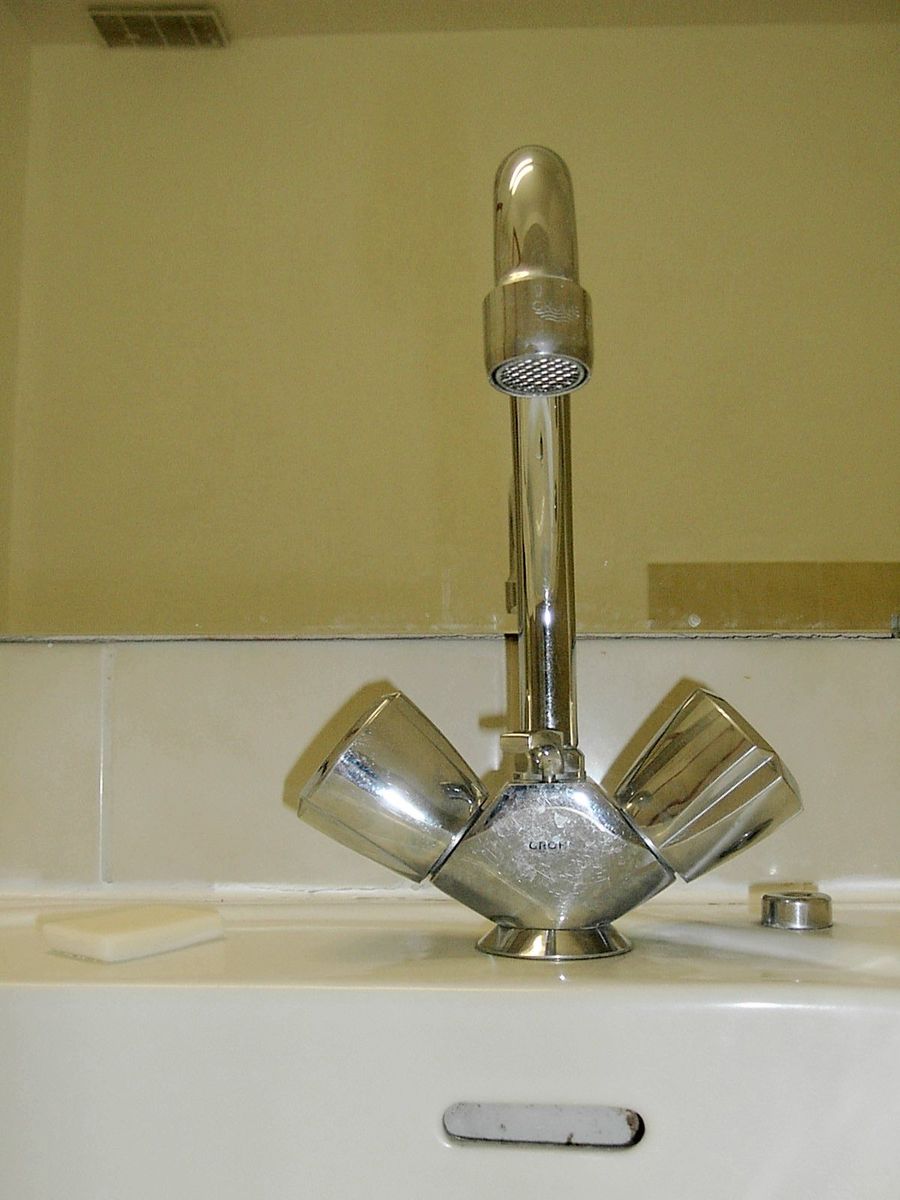 there is a sink with a toothbrush and two cups sitting on top of it