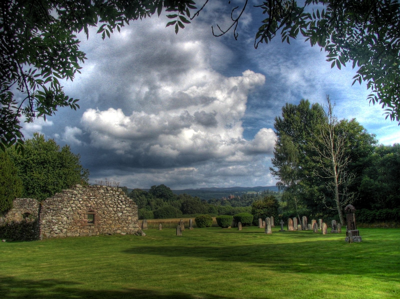 trees, grass and a stone house in a field