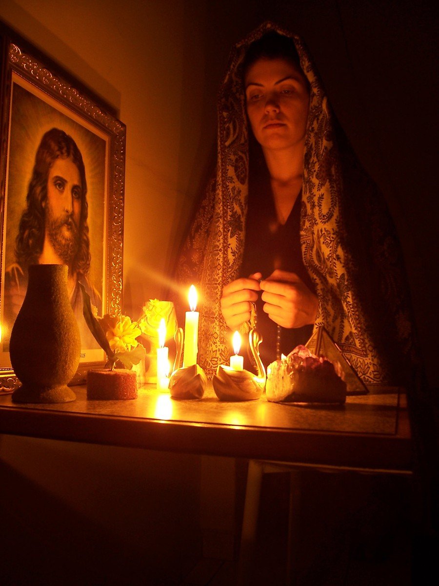 a woman in black holding a cellphone near candles