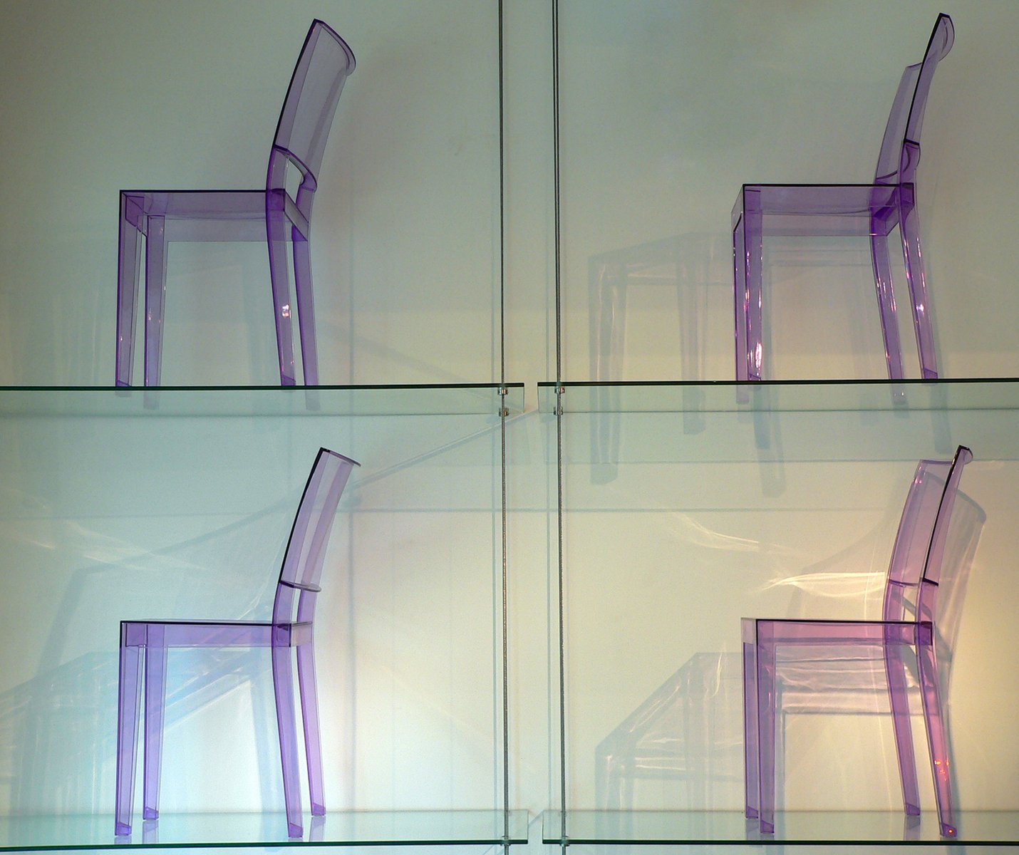 clear chairs sit against glass display cases in a museum