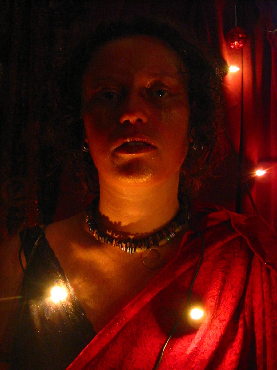 a woman wearing a red cape standing next to some candles