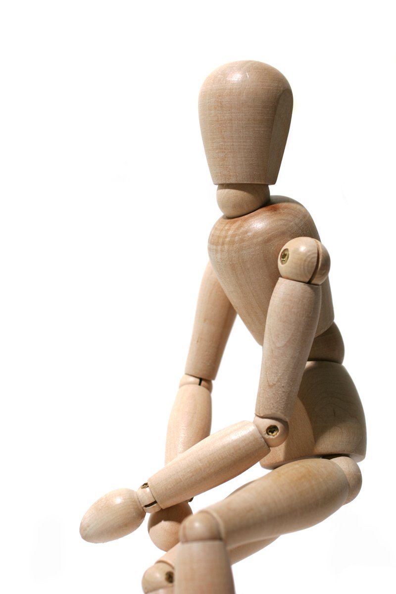 a wooden figurine of a person holding a stick