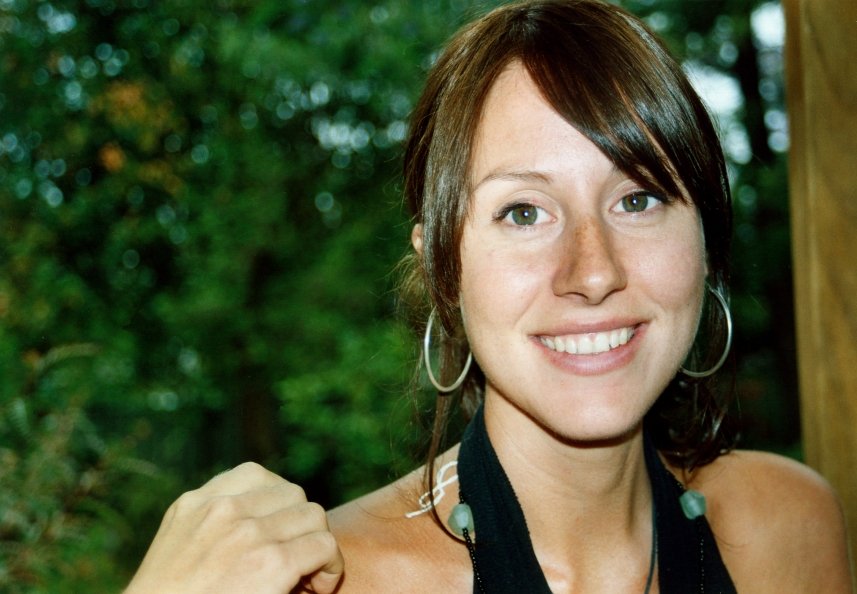 a woman standing near trees in a forest