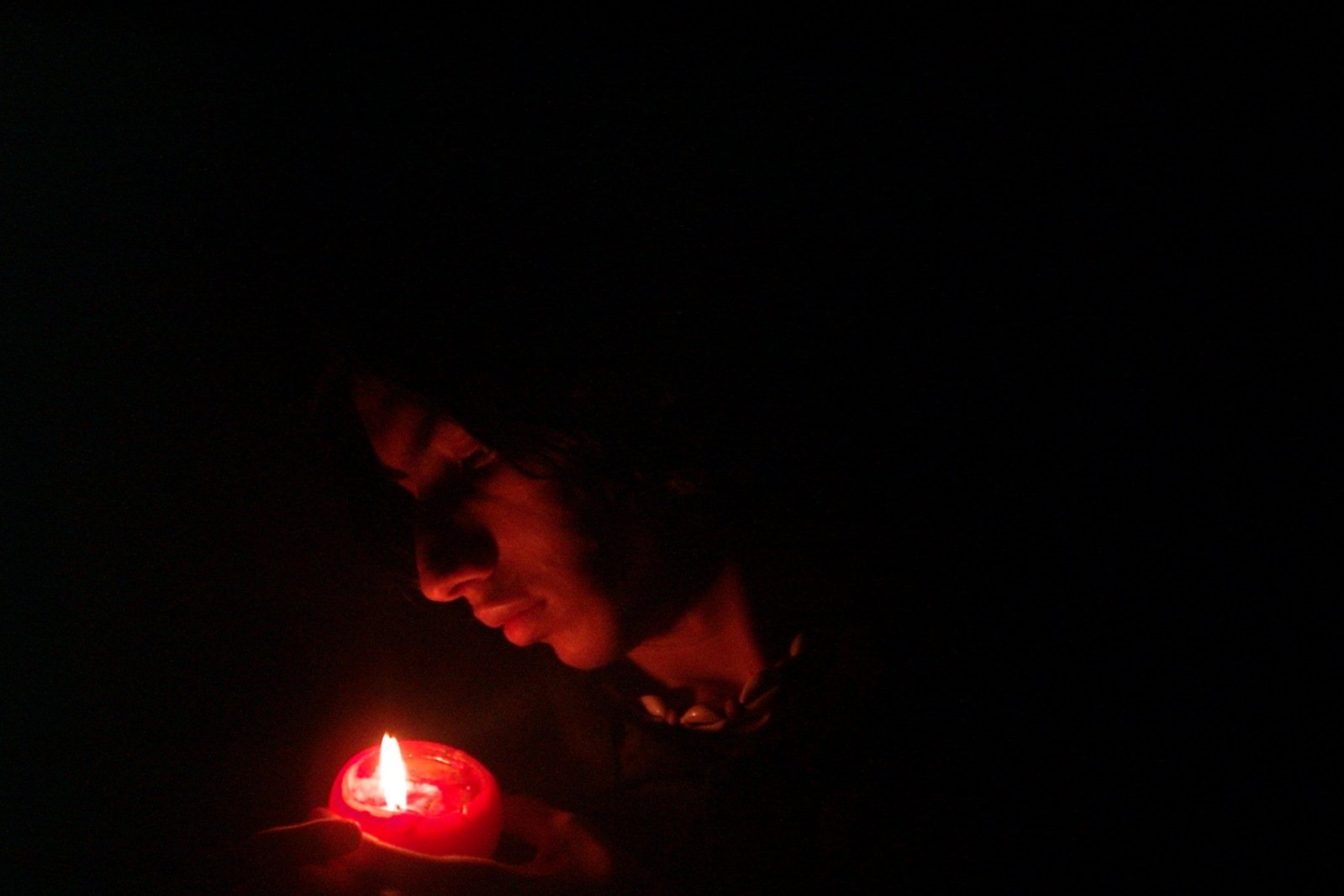 a woman holding a red candle in the dark
