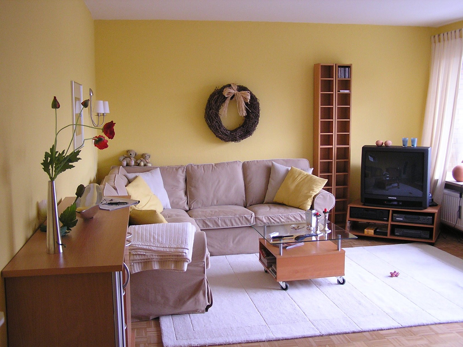 a yellow living room with white rugs and an old fashioned tv
