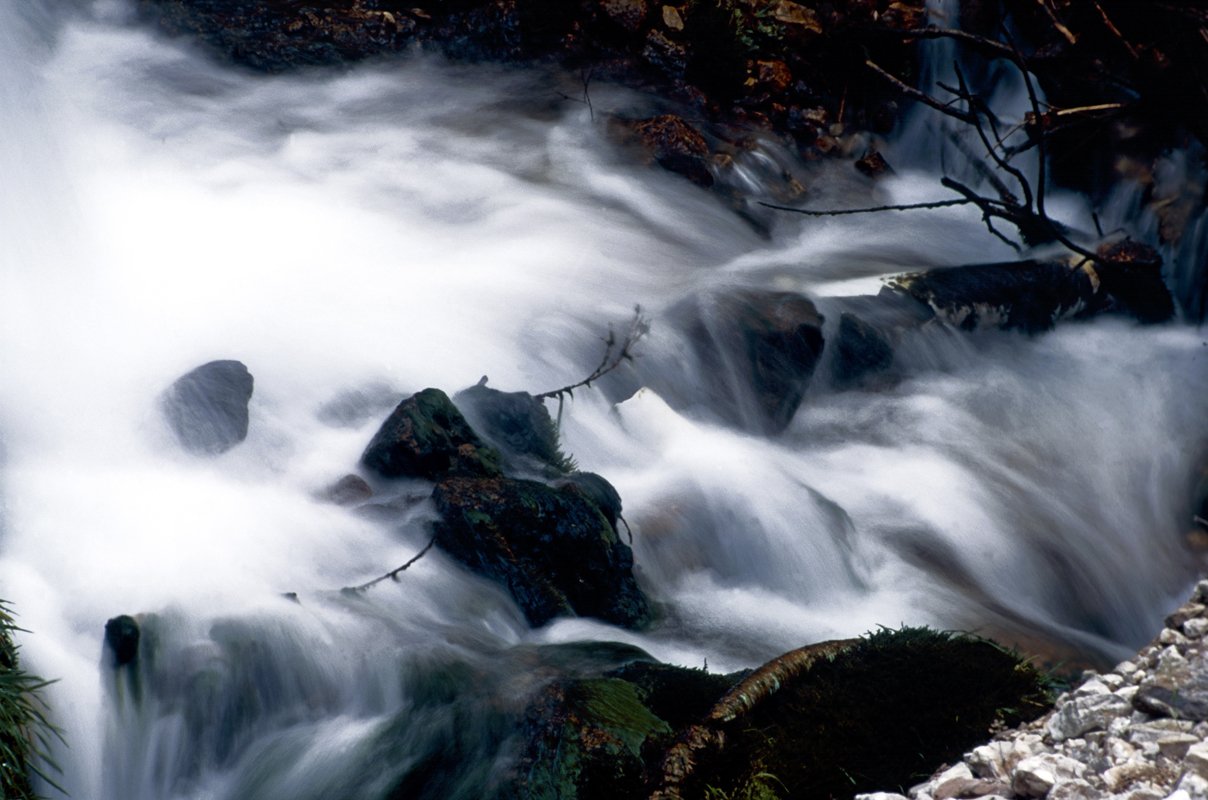 water flows over rocks on the edge of a body of water