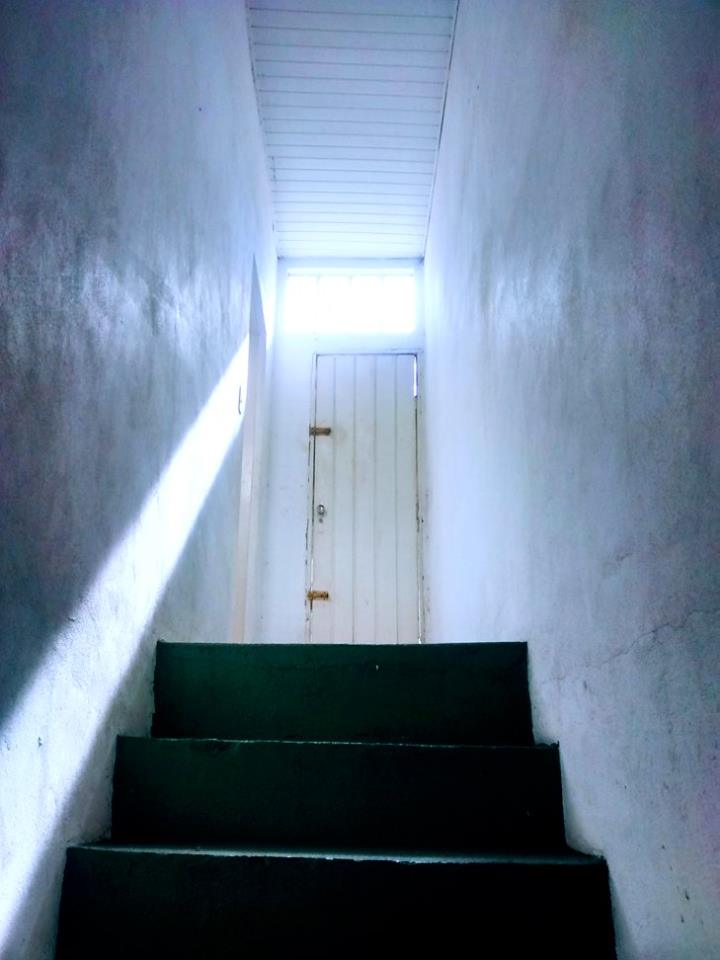 an alleyway is narrow with stairs leading to a light