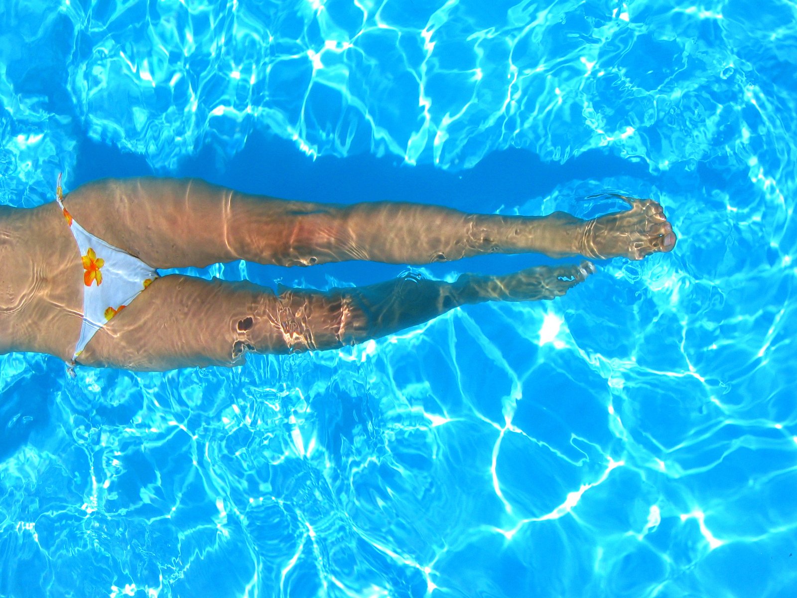 a person with white bikini swimming in blue water