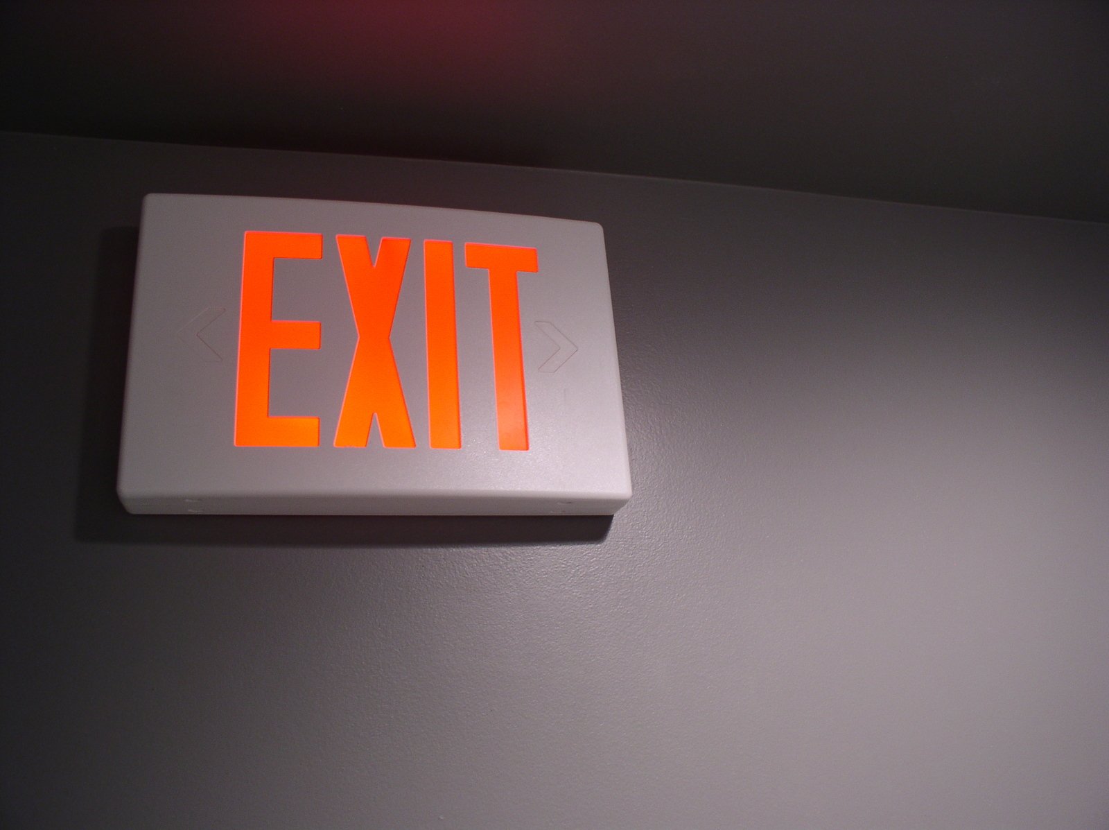 an exit light on a white wall in a hallway
