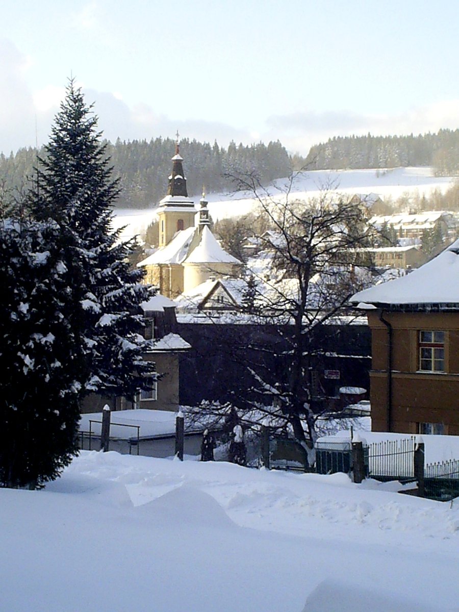 houses in the snow with a clock tower behind them