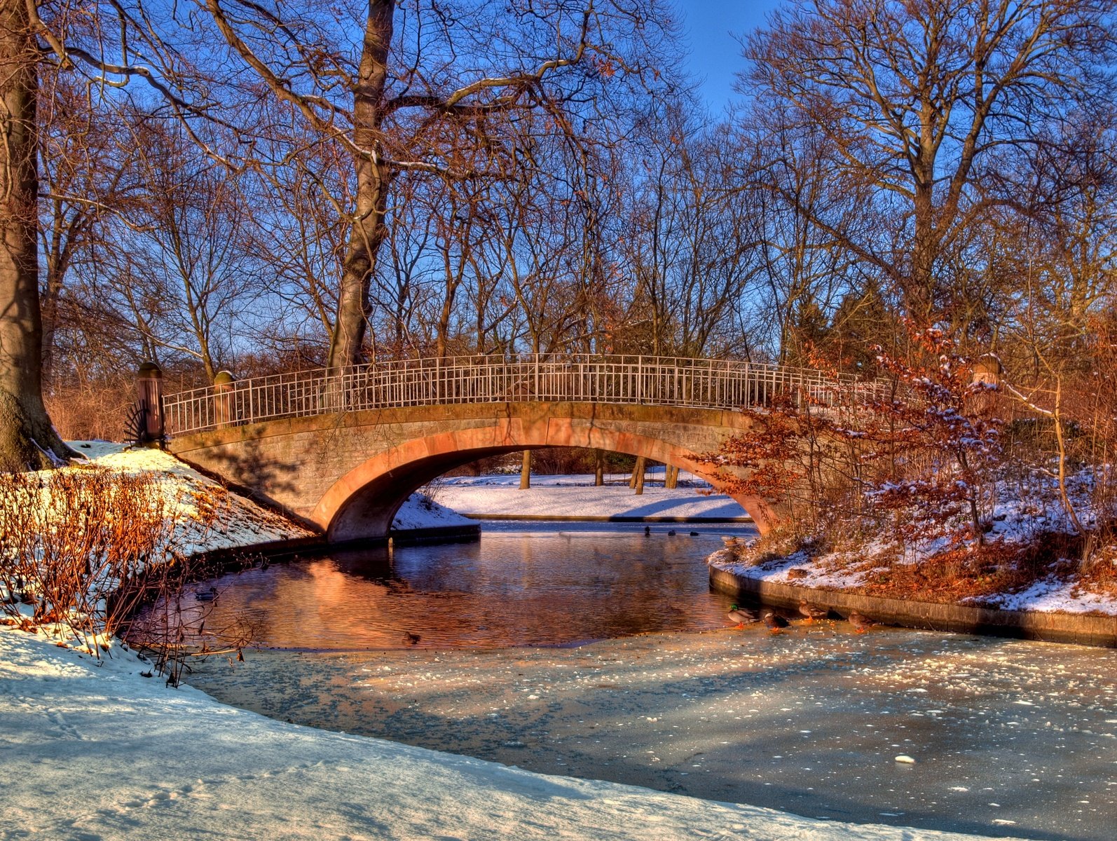 bridge with arch over river surrounded by snow